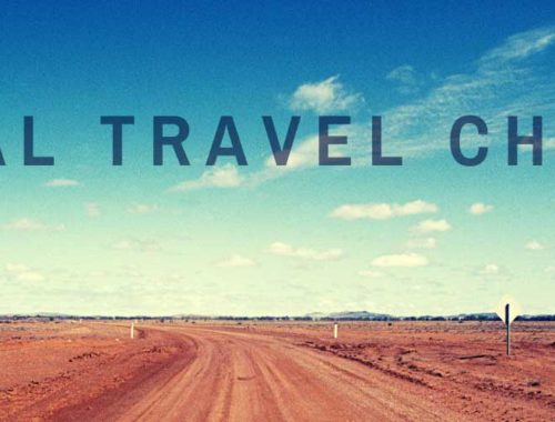 Image contains a photo of a long dirt road heading to the horizon. The sky above is mostly clear and blue with a few small white clouds. In the foreground, there is black text that says "Global Travel Channel".