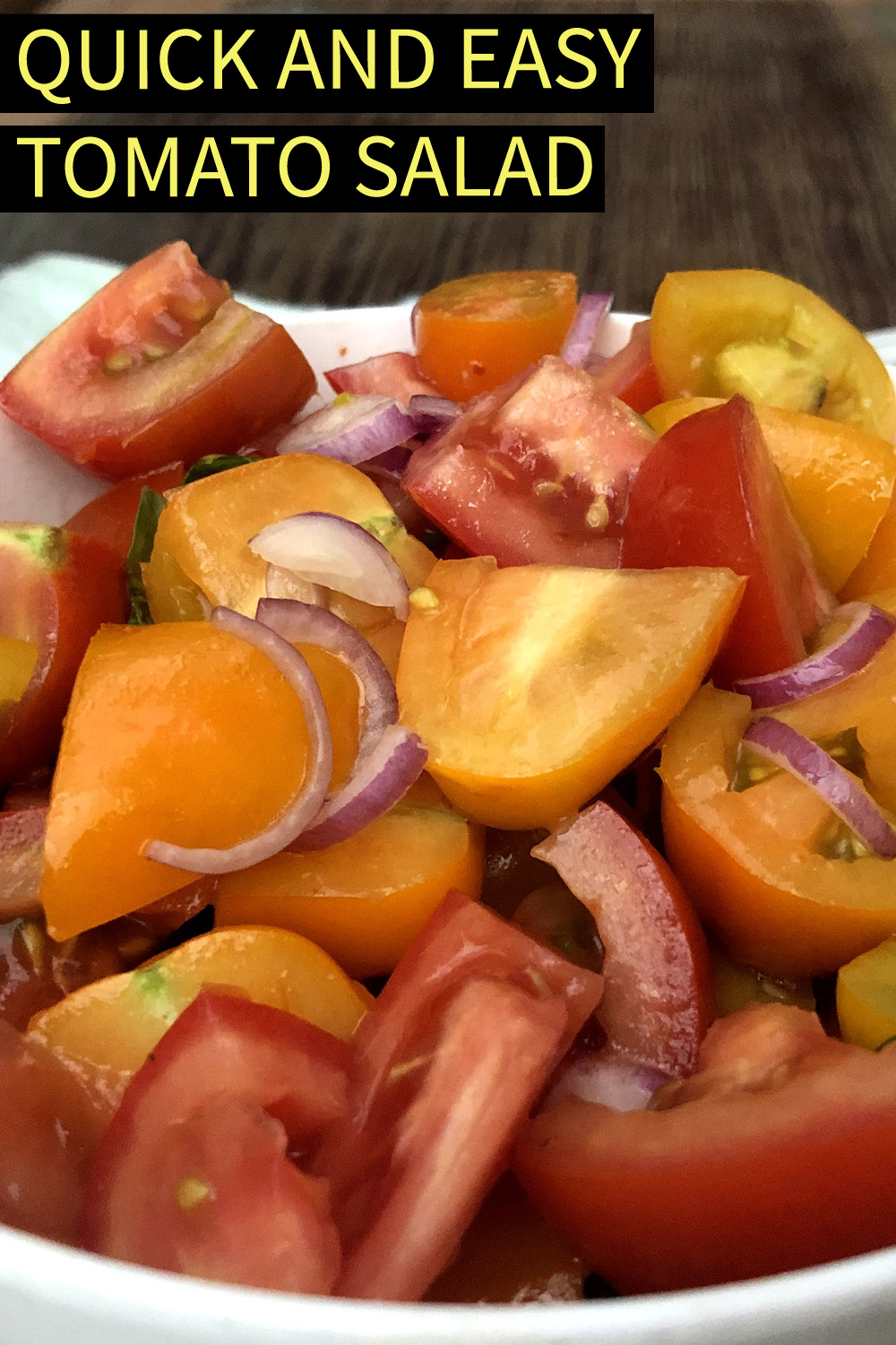 Image contains a photo of a bowl of chopped tomatoes with red onion, basil, chili flakes, oil, and vinegar. Above the bowl, there is white text on a black background that says "Quick and Easy Tomato Salad".