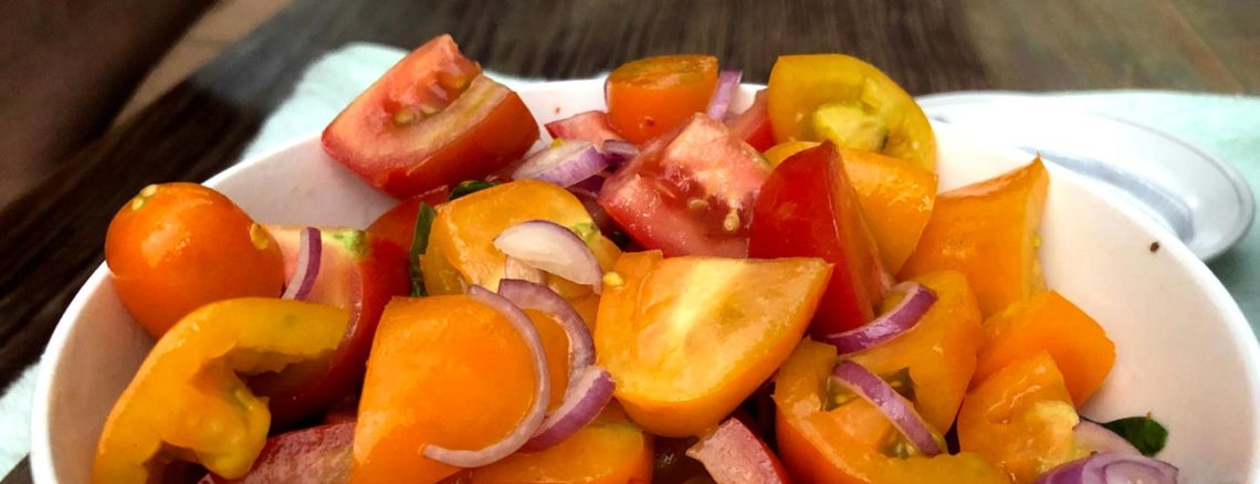 Image contains a photo of a bowl of chopped tomatoes with red onion, basil, chili flakes, oil, and vinegar.