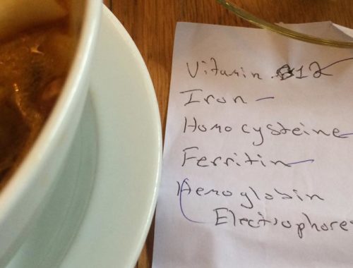 Image contains a photo of a white bowl of soup and noodles on the left, a glass cup of tea in the top right-hand corner, and a paper note in the bottom right-hand. On the note, there is handwriting that says "Vitamin B12, iron, homocysteine, ferritin, and hemoglobin electrophoresis."